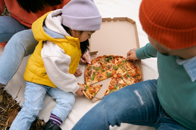 Family eating pizza outdoors high angle