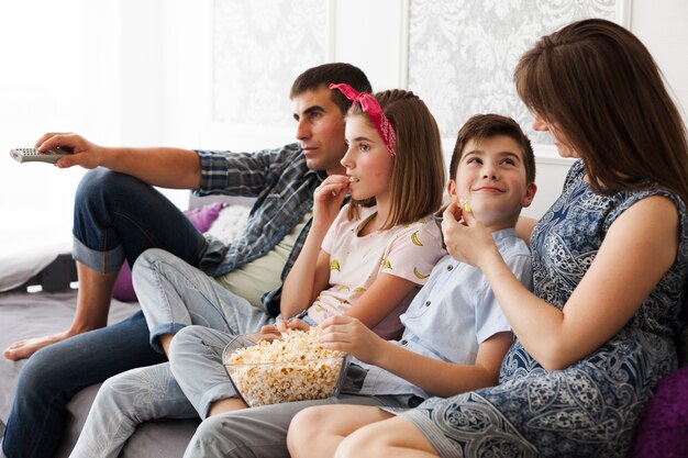 집에서 텔레비전을 보면서 팝콘을 먹는 가족