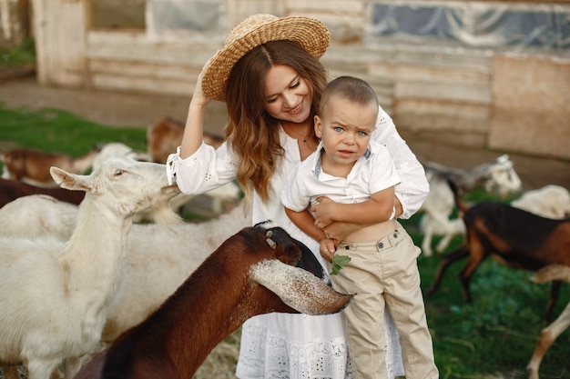 Foto gratuita famiglia in una fattoria. persone che giocano con una capra. madre con figlio.