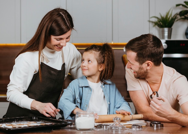 Семья отца и матери с дочерью готовит вместе на кухне