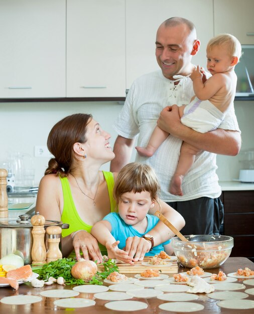 family of four together in the kitchen prepares food