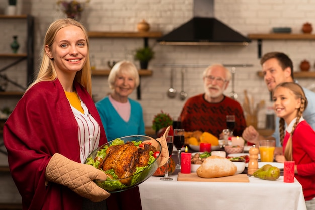 Family generations at the thanksgiving table and mother bringing the turkey