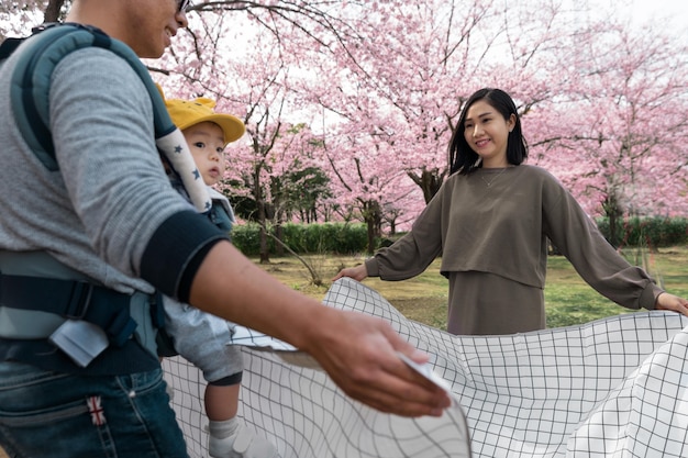 桜の横でピクニックをしている家族