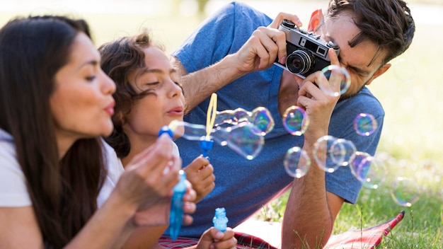 Семья веселится в парке, пуская мыльные пузыри