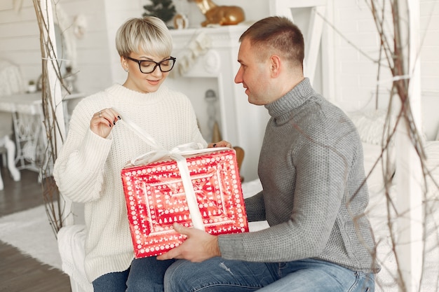 家にいる家族。クリスマスの飾りの近くのカップル。灰色のセーターを着た女性。