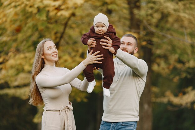 Бесплатное фото Семья в осеннем парке. мужчина в коричневом свитере. милая маленькая девочка с родителями.