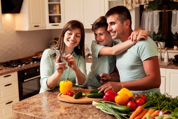 Семья на кухне, глядя на фотографии на смартфоне