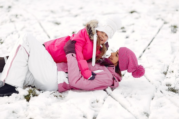 Family in knitted winter hats on family Christmas vacation. Woman and little girl in a park. People playing.