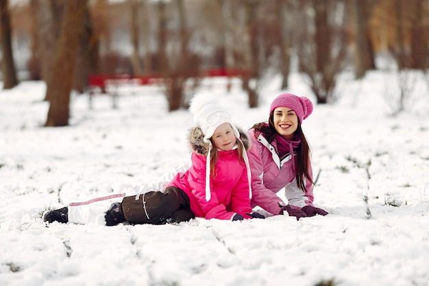 Family in knitted winter hats on family Christmas vacation. Woman and little girl in a park. People playing.