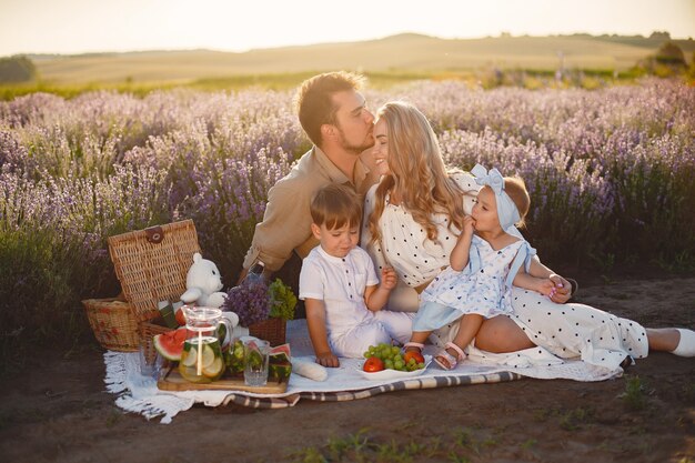 Family on lavender field. People on a picnic. Mother with children eats fruits.