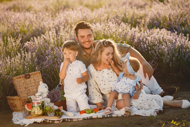 Free photo family on lavender field. people on a picnic. mother with children eats fruits.