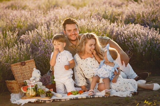 Family on lavender field. People on a picnic. Mother with children eats fruits.