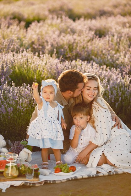 Family on lavender field. People on a picnic. Mother with children eats fruits.