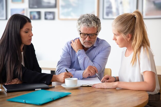 Family legal advisor explaining document details to mature father and adult daughter