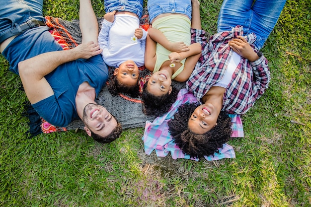 Foto gratuita famiglia sdraiata sull'erba guardando verso il cielo