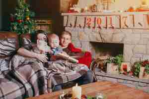 Free photo family lying on the sofa covered with a blanket while they look at a book and on the table there is a lit candle