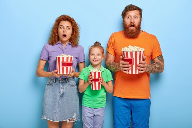 family members enjoy watching television with popcorn