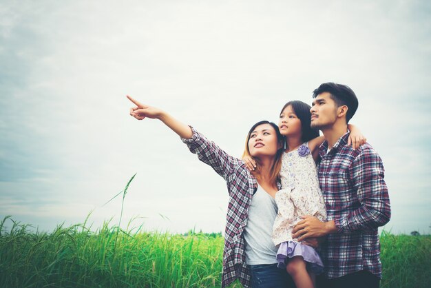 Family of mother, father and child on meadow, dad carrying the d