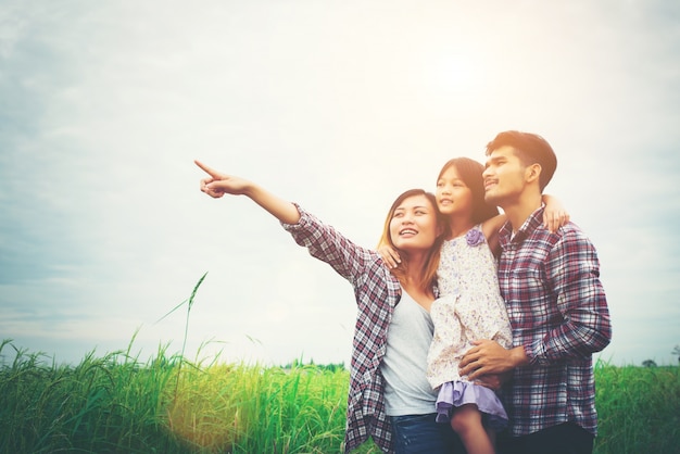 Free photo family of mother, father and child on meadow, dad carrying the d