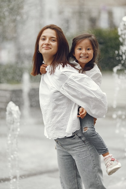 Free photo family near the city fountain. mother with gaughter playing with water.