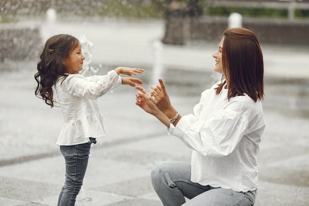 Famiglia vicino alla fontana della città. madre con la figlia che gioca con l'acqua.