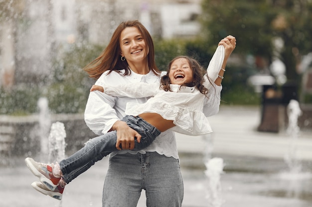 Family near the city fountain. mother with gaughter playing with water.