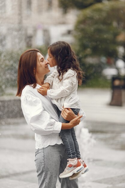 Family near the city fountain. Mother with gaughter playing with water.