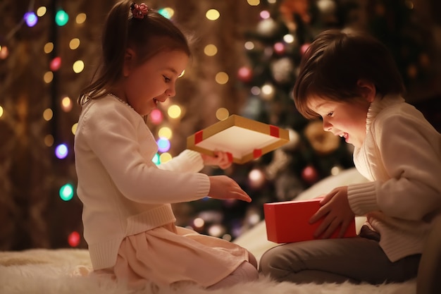 暖炉のクリスマスイブの家族 クリスマスプレゼントを開く子供たち ギフトボックスとクリスマスツリーの下の子供たち 伝統的な暖炉のある装飾されたリビングルーム 自宅で居心地の良い暖かい冬の夜 プレミアム写真 暖炉のクリスマスイブの家族 クリスマスプレゼントを開く子供たち ギフトボックスとクリスマスツリーの下の子供たち 伝統的な暖炉のある装飾されたリビングルーム 自宅で居心地の良い暖かい冬の夜 プレミアム写真