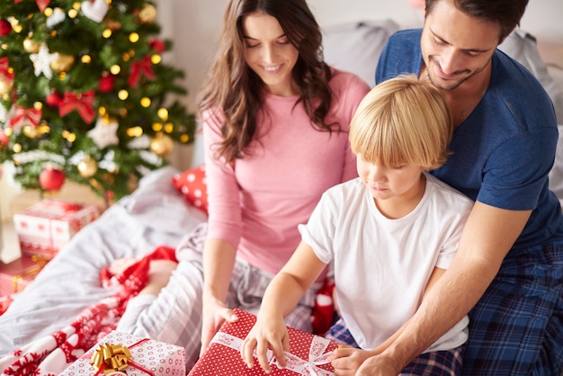 Family opening Christmas presents in the bed