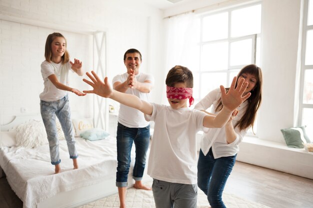 Family playing blind man's buff in bedroom