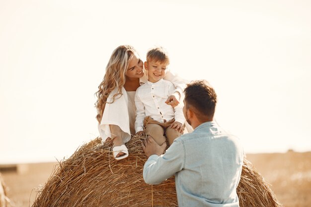日没時に麦畑で赤ちゃんの息子と遊ぶ家族。夏休みのコンセプト。自然に一緒に時間を過ごす家族。