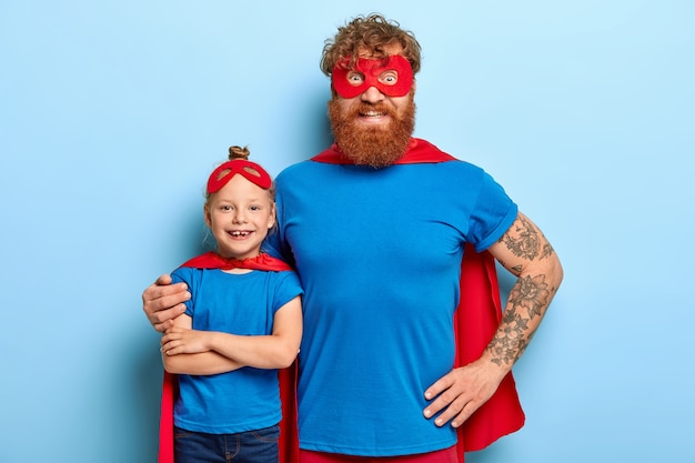 Семейный портрет забавного отца и дочери, играющего супергероя
