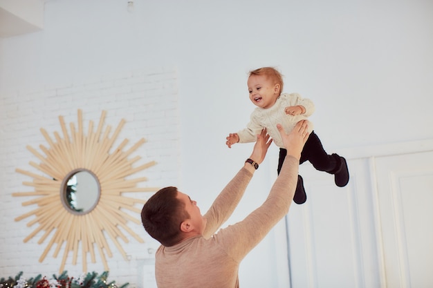 Foto gratuita ritratto di famiglia. il padre felice tiene la bambina felice in braccio in piedi nella stanza accogliente