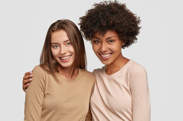 Family portrait of happy mixed race sisters hug each other, have satisfied expressions