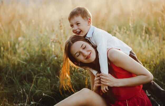 家族の肖像画、自然。魅力的なママと息子が芝生で遊ぶb