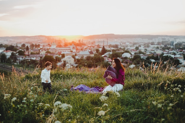 Family portrait. Nature. Mom plays with a sun holding pillows in