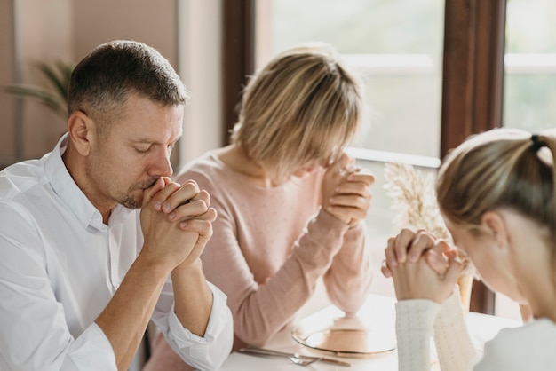 Семья вместе молится перед едой в помещении