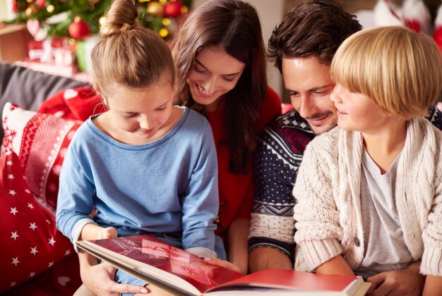 Семья, читающая книгу на Рождество