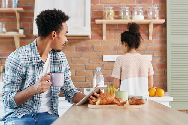 Family relationship, routine concept. Mixed race dark skinned Afro American male uses tablet for communication online