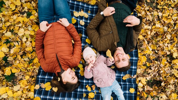 Family relaxing on autumn leaves in park