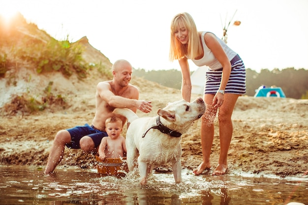 "Family relaxing on shore with dog"
