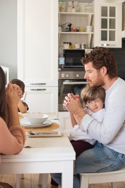 Family saying a prayer together at home