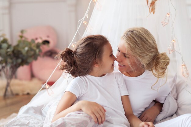 Family scene. Happy mother and daughter in a bed