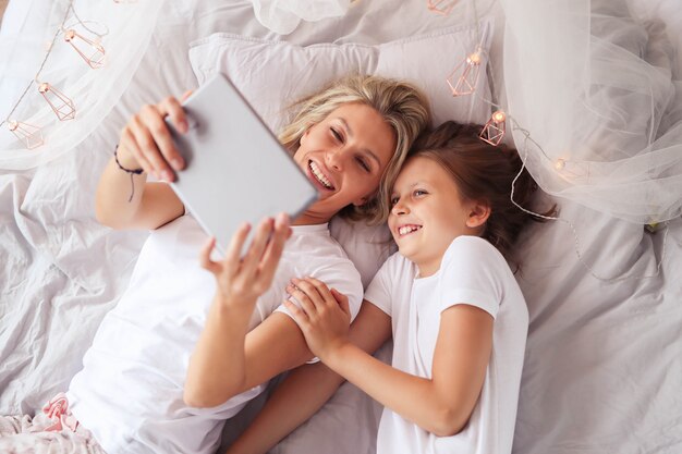 Family scene. Happy mother and daughter in a bed