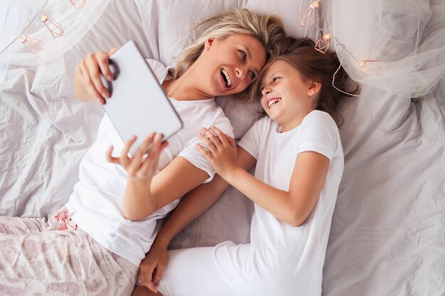 Family scene. Happy mother and daughter in a bed