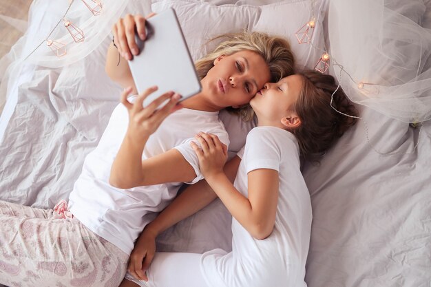 Family scene. Happy mother and daughter in a bed