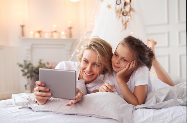 Family scene. Happy mother and daughter in a bed