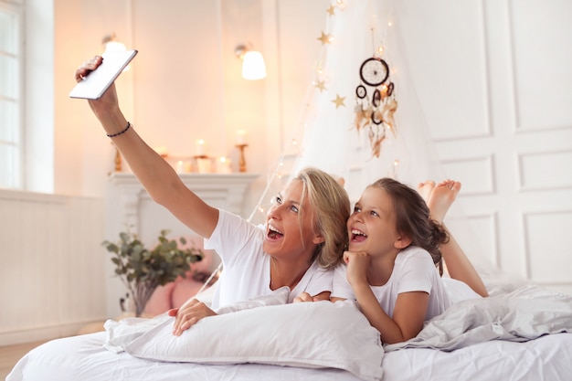 Family scene. Happy mother and daughter in a bed