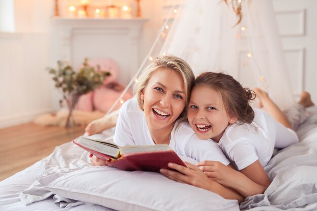 Family scene. Happy mother and daughter in a bed
