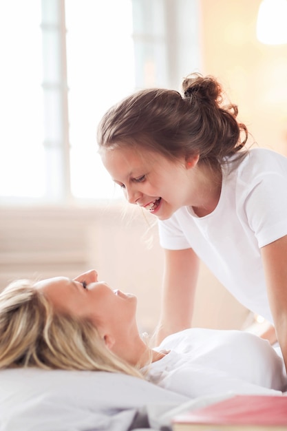 Family scene. Happy mother and daughter in a bed